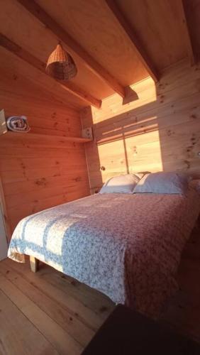 una camera da letto con un letto in una cabina di legno di Cabaña Orca Lodge Norte frente al mar en Curanipe, Desconéctate para reconectar a Curanipe