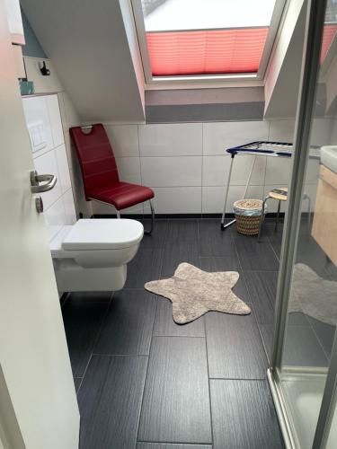 a bathroom with a toilet and a red chair at Haus Julianne, Wohnung Backbord, Familie Poppinga in Norderney