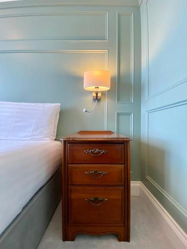 a bedroom with a bed and a nightstand with a lamp at The Fairhaven Hotel in Weymouth