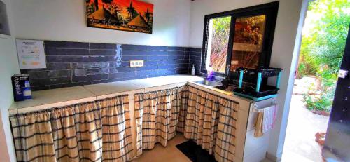 a kitchen with a counter with a sink and a window at Chambres d'hôtes Les Cases BéNaDou in Ngaparou