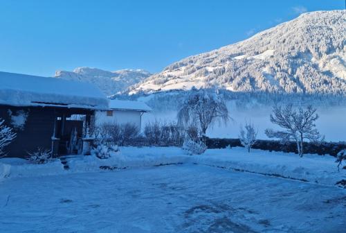 a house covered in snow in front of a mountain at Ferienwohnung Wallner in Zell am Ziller