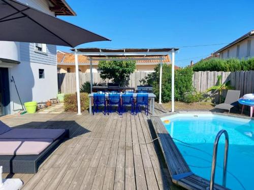un patio avec une table et des chaises à côté d'une piscine dans l'établissement Villa élégante à Biscarrosse avec piscine privée, à Biscarrosse