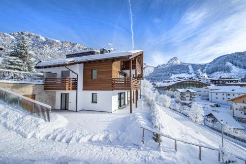 a building in the snow with a mountain in the background at Apartments Chalet Silva in Selva di Val Gardena