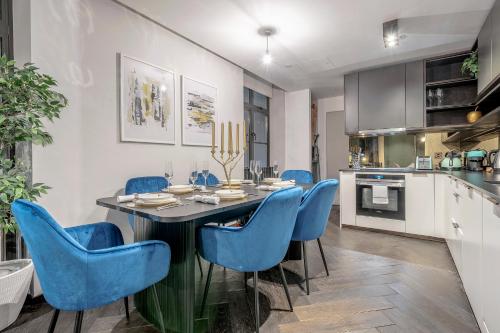 a kitchen and dining room with a table and blue chairs at The Soho STAR in London