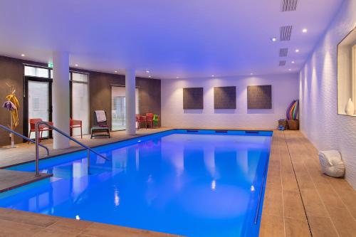 a large pool with blue water in a building at DOMITYS Résidence Séniors - La Palangre in Le Tréport