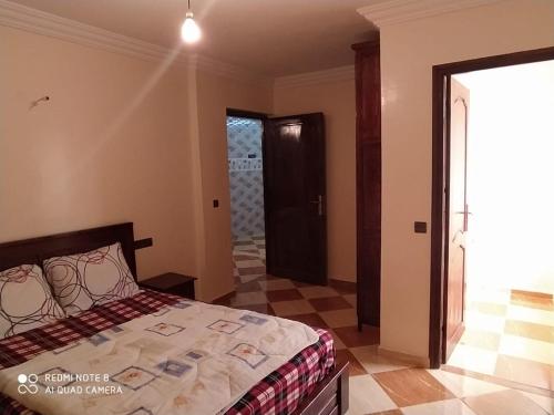 1 dormitorio con 1 cama y puerta al baño en Maison Lahoucine en Sidi Ifni