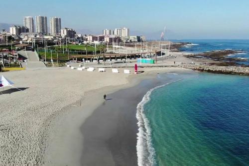 a beach with white umbrellas and the ocean at Departamento moderno, vista al mar y estacionamiento incluido in Antofagasta