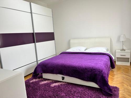 a bedroom with a purple comforter on a bed at Apartmani Andric in Trebinje
