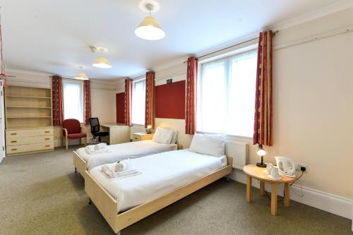 um quarto de hotel com duas camas e uma secretária em Selwyn College, Cambridge em Cambridge