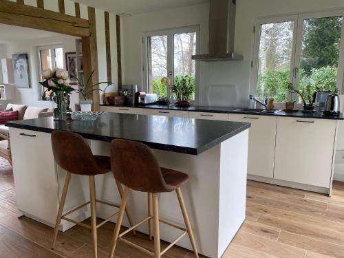 une cuisine avec des armoires blanches et un comptoir noir dans l'établissement La Petite chaumière normande, à Tourville-en-Auge