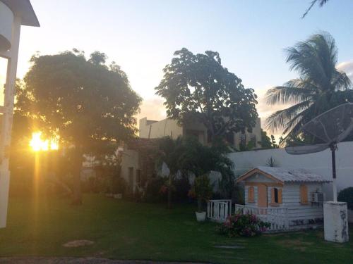 a house with the sun setting in the yard at Casa América in Parnaíba
