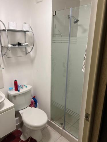 uma casa de banho com um WC e uma cabina de duche em vidro. em Lindo Apartamento en Condominio Privado em Lima