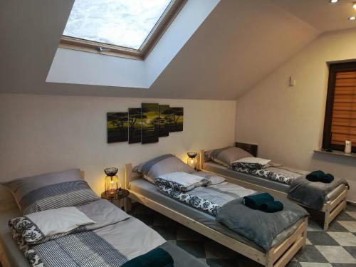 three beds in a room with a skylight at Apartament Pod Bukami in Łaziska Górne