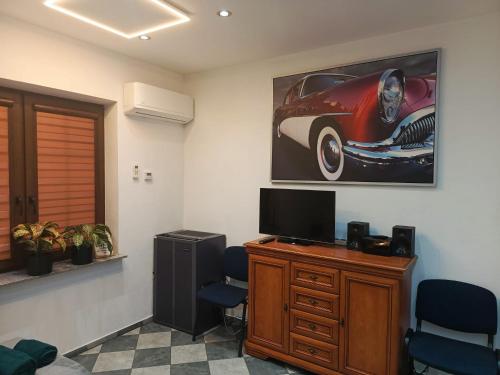 um quarto com uma secretária com uma televisão e uma fotografia de um carro em Apartament Pod Bukami em Łaziska Górne