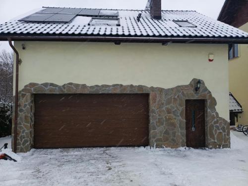 a building with a brown garage door in the snow at Apartament Pod Bukami in Łaziska Górne