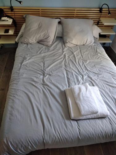 - un lit blanc avec 2 oreillers et une serviette dans l'établissement Le jasmin du Riou, à Cannes