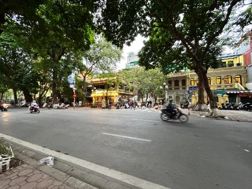 a person riding a motorcycle down a city street at NHÀ AN in Hanoi