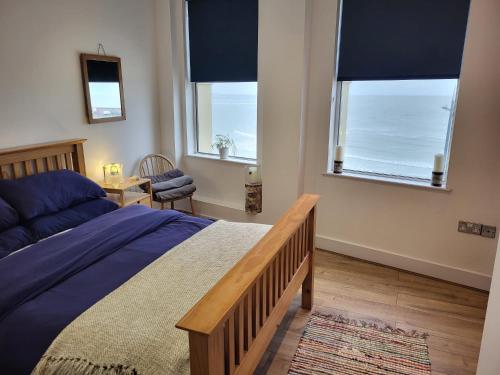 um quarto com uma cama e duas janelas com o oceano em Imperial House "Serviced Apartments" em Margate