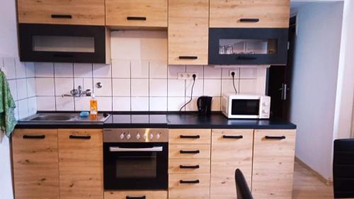 a kitchen with wooden cabinets and a microwave at Museum Park Szell str B- Downtown 1 Bedroom+Living Room apartment in Szombathely