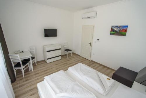 a living room with a white bed and a desk at BL Garden Panzió in Balatonlelle
