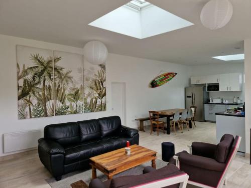 un salon avec un canapé en cuir noir et une table dans l'établissement Maison plain-pied entièrement neuve / 4 chambres, à Saint-Cast-le-Guildo