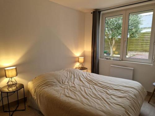 une chambre avec un lit et deux lampes et une fenêtre dans l'établissement Maison plain-pied entièrement neuve / 4 chambres, à Saint-Cast-le-Guildo
