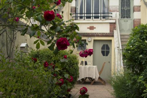 a garden with roses and a table and a building at Honfleur house in Honfleur