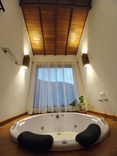 a bath tub in a room with a window at Chalé Canarinho in São Pedro da Serra