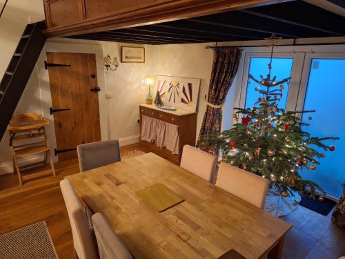 a dining room with a table and a christmas tree at Mayeston Barn Holiday Home in Pembroke Dock