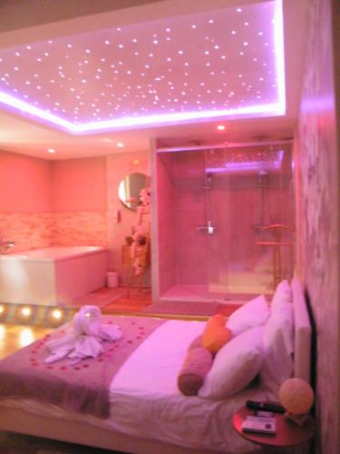 Studio Love Spa Baignoire XXL Port Vieux La Ciotat في لاسيوتا: غرفة نوم مع سرير ودش مع اضاءة ارجوانية