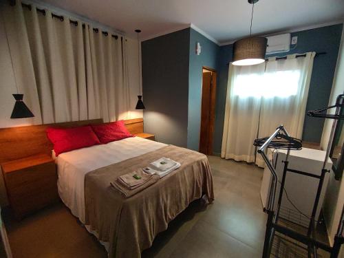 um quarto com uma cama com almofadas vermelhas e uma janela em Vitória Suítes - Vila de São Jorge em São Jorge