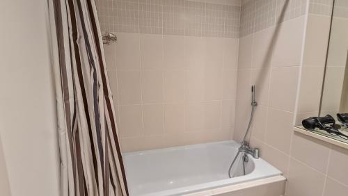 a bathroom with a white tub and a shower curtain at River View Private Room in Shared Apartment in Belfast