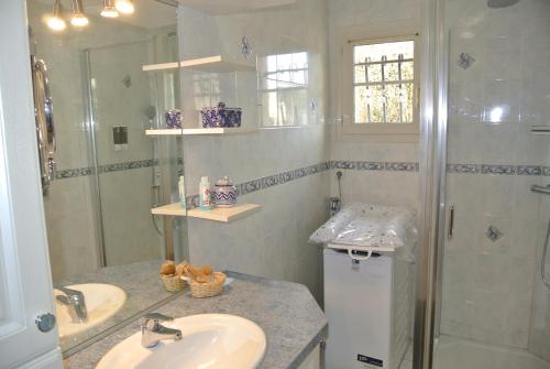 a white bathroom with two sinks and a shower at Gîte Les Chênes in Villeneuve-les-Sablons