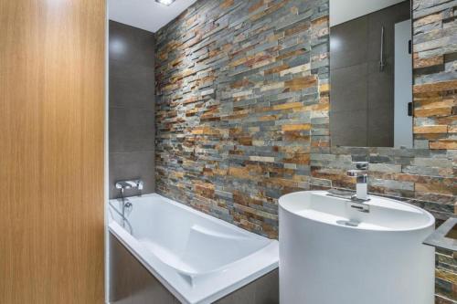 a bathroom with a white sink and a brick wall at Résidence Les Sapins - Courchevel 1850 in Courchevel