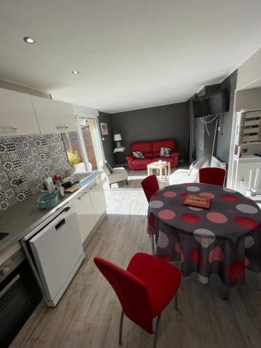 eine Küche und ein Wohnzimmer mit einem Tisch und roten Stühlen in der Unterkunft ALS locations calvet françoise in Jonzac