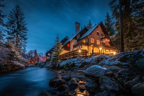 a house in the woods at night with a stream at Chata Liptov in Liptovský Ján