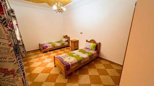 a living room with two beds and a checkered floor at dar haut de gamme Et à un prix imaginaire Hostcom in Oujda