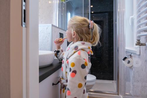 a little girl brushing her teeth in a bathroom at Camping de Pallegarste - voor uw vakantiebestemming! in Mariënberg