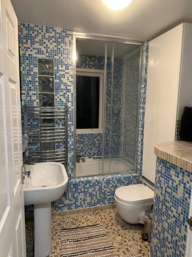 a blue tiled bathroom with a toilet and a sink at TJ House in Sherborne Saint John