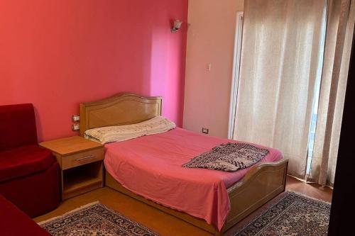 una piccola camera con letto e parete rossa di Super Cozy Apt 7 min to CAI a Il Cairo