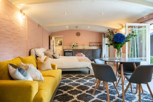 a living room with a yellow couch and a bed at Guest House in Audley End in Saffron Walden