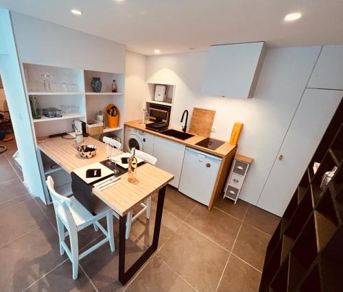 a kitchen with a dining table and a kitchen with white cabinets at Plongez dans le charme et le mystère de la maison Mythique in Andenne