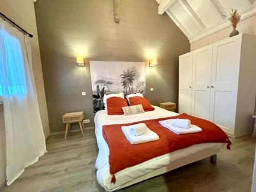 a bedroom with a large bed with two towels on it at Gite de Mortagne, Chalet avec Piscine - BY PRIMO C0NCIERGERIE in Gigny-sur-Saône