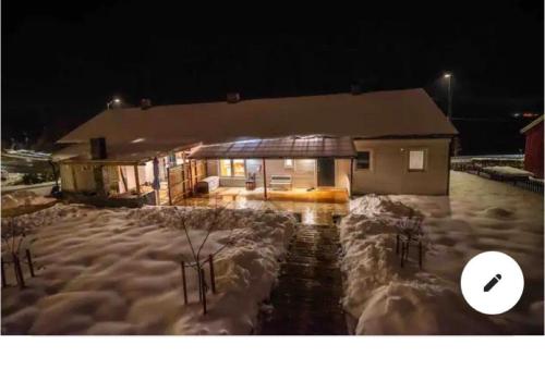 a house is covered in snow at night at Sea view Holmestrand sauna and hot tube appartment in Holmestrand