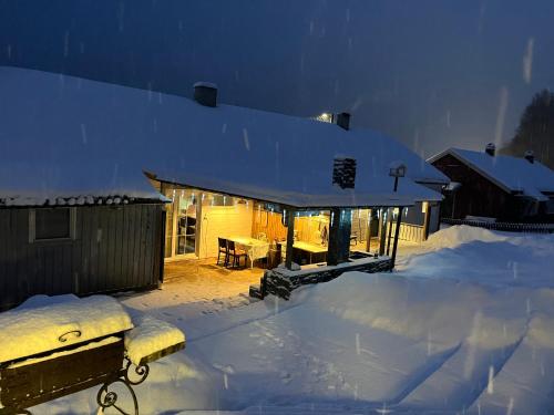 a house covered in snow with a bench in front at Sea view Holmestrand sauna and hot tube appartment in Holmestrand