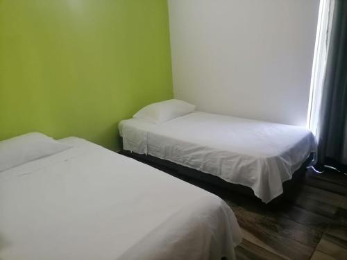 duas camas num quarto com paredes verdes em Casa Club Caminos del Peñón em El Brasil