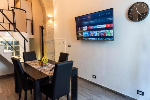 een eetkamer met een tafel en een tv aan de muur bij Lannari 176 Casa vacanze Bagheria in Bagheria