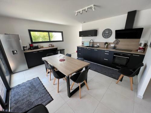 une cuisine avec une table en bois et des placards noirs dans l'établissement Villa Chez Louise, à Vaux-sur-Mer
