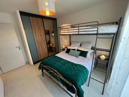 - une chambre avec des lits superposés et une couverture verte dans l'établissement Villa Chez Louise, à Vaux-sur-Mer