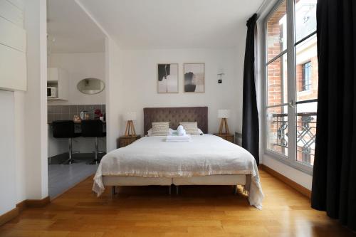 1 dormitorio con cama y ventana grande en Appartement service - Vue sur le Musée - Paris 5, en París